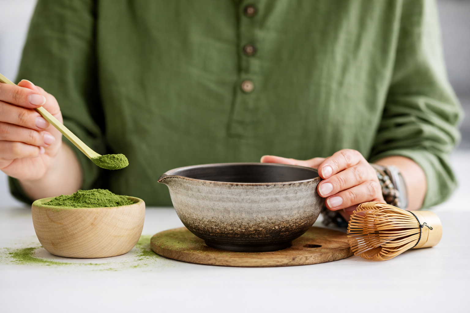 Matcha Pulver wird mit Bambuslöffel (Chashaku) in traditionelle Matcha Schale gefüllt, Chasen liegt daneben